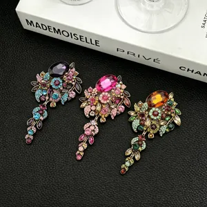 Detail view of three vintage rhinestone floral brooches with colorful glass tassels