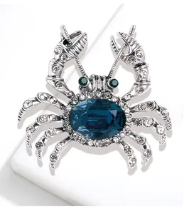 Close-up of a crab brooch featuring a large blue gemstone and clear rhinestones