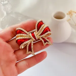 Vue détaillée d'une broche nœud en émail rouge avec d'élégantes décorations en perles blanches