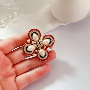 Détail en gros plan d'une broche vintage en émail et perles de style français à la main