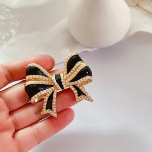 Gros plan détaillé d'une broche nœud en émail noir de style vintage avec perles.