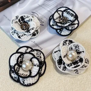 Vue détaillée des broches camélia en tweed avec d'élégantes perles et cristaux