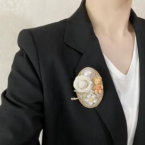 Dettaglio ravvicinato di una spilla barocca con orsetto di perle su un blazer nero