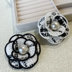 Gros plan détaillé de broches camélias en tweed avec de grandes perles centrales