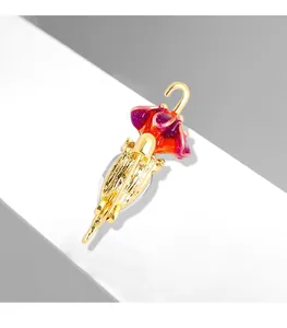 Macro dettagliata di una spilla a forma di ombrello dorato con smalto sfumato rosso