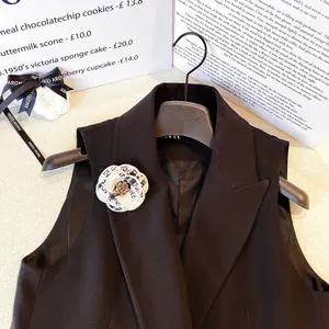 Élégante broche camélia en tweed avec strass sur le revers d'un gilet noir chic