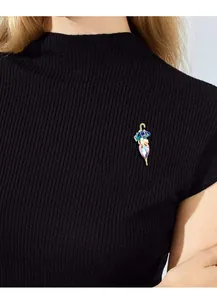 Primo piano di una spilla a forma di ombrello con cristalli su un maglione nero a coste.
