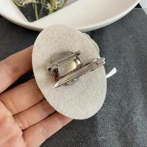 Primo piano del retro di una spilla vintage con spilla di sicurezza e fermaglio a coccodrillo.