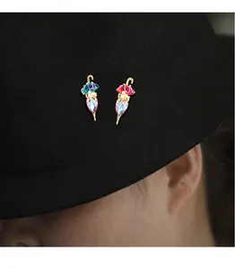 Primo piano di eleganti spille a forma di ombrello con strass colorati su un cappello nero.