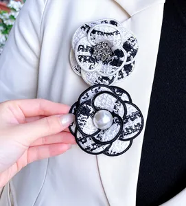Vue détaillée d'élégantes broches camélia en tweed avec perles et strass brillants