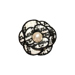 Élégante broche camélia style Chanel avec texture en tweed et perle centrale blanche