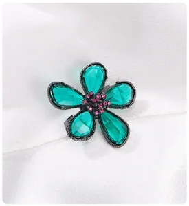 Detaillierte Ansicht einer eleganten Blumenbrosche mit blaugrünen Kristallen und Akzenten