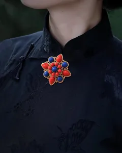 Detail view of ethnic lotus brooch with red and blue beads pinned on a dark cheongsam.