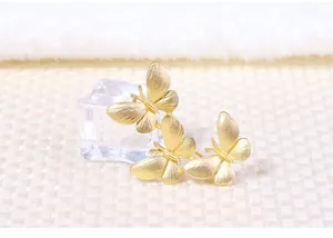 Detailed view of matte gold three-butterfly brooch with intricate wing textures