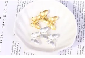 Close-up of matte gold and silver three-butterfly brooches in a decorative bowl