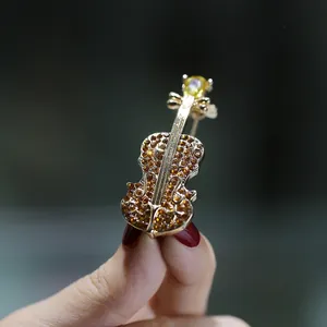 Close-up of elegant crystal violin brooch with gold finish and amber rhinestones