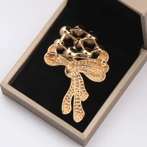 Macro detail view of a luxury golden pearl floral brooch in a jewelry gift box.