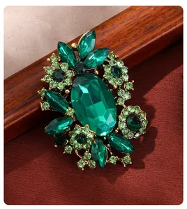 Macro detail of a vintage emerald green crystal brooch featuring intricate floral designs