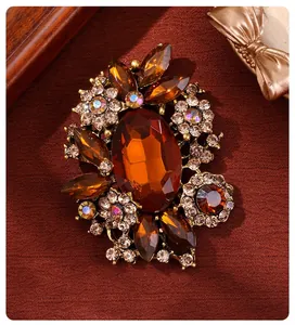 Detailed macro view of a vintage amber glass brooch featuring floral rhinestone motifs