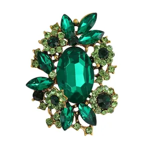 Elegant vintage green rhinestone floral brooch pin featuring large oval glass stone centerpiece
