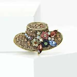 Vintage sun hat brooch encrusted with multi-colored rhinestones on white geometric blocks.