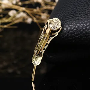 Detailed macro view of the back clasp and hollow texture on a gold feather brooch.