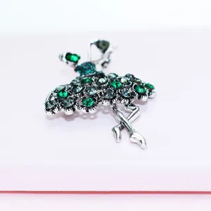 Detailed macro shot of a dancing ballerina brooch with sparkling green rhinestones.