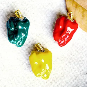 Macro view showing three colorful enamel chili pepper brooches with sparkling crystals.