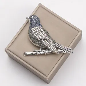 Detailed close-up of a heavy craft rhinestone robin brooch on a jewelry box