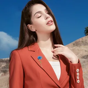 Elegant blue carnation flower brooch pin for women styled on a professional orange blazer