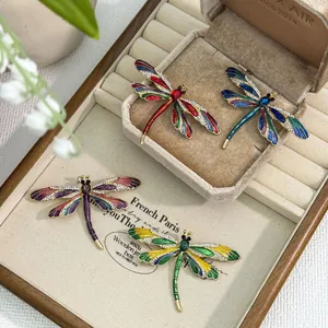 Close-up of colorful enamel dragonfly brooches with rhinestones on a jewelry box