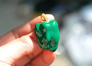 Detailed close-up of a glossy green pepper brooch featuring sparkling gold diamond bail.