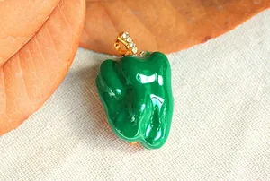 Macro detail of a vibrant green enamel bell pepper brooch with sparkling crystal stem.