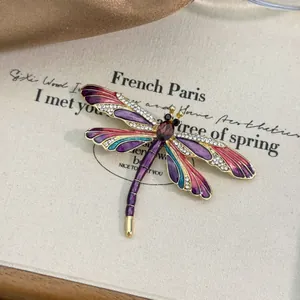Close-up of elegant enamel dragonfly brooch with colorful wings and rhinestones
