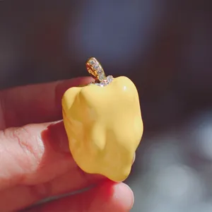 Detail view of a yellow enamel bell pepper brooch with a sparkling rhinestone stem.