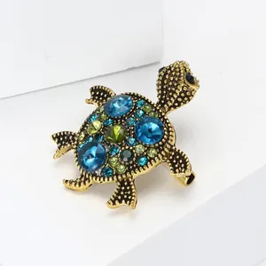 Detailed view of a vintage gold alloy turtle brooch with blue and green rhinestones