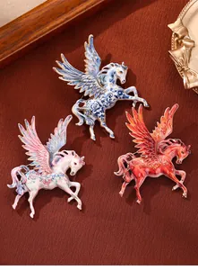 Detailed view of three colorful enamel Pegasus wing horse brooches on red surface