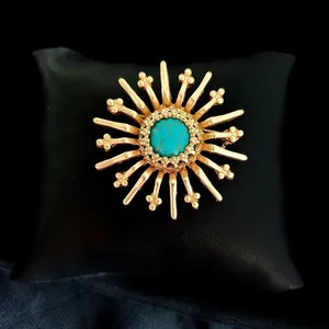 Macro view of vintage Baroque brooch with matte gold finish and turquoise stone