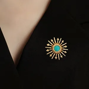 Detailed view of vintage Baroque sunburst gold brooch with turquoise stone on blazer