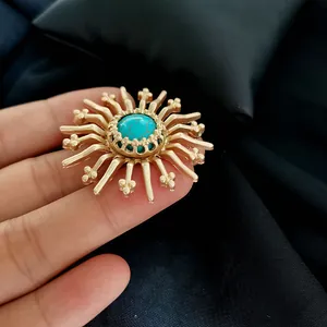 Close-up of a vintage Baroque matte gold brooch featuring a central turquoise stone.