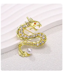Detailaufnahme einer eleganten goldenen Drachenbrosche mit Strass und weißer Perle