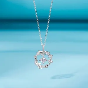 Detail van een elegante zilveren halsketting met een hanger van twee dolfijnen en steen