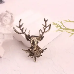 Close-up of a vintage bronze alloy deer head brooch with detailed antlers on a white base