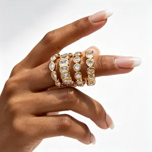 Close-up view of four stacked gold stainless steel rings with various zircon stone shapes.