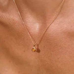 Nahaufnahme einer 18K vergoldeten Halskette mit ovalem orangefarbenem Edelstein.