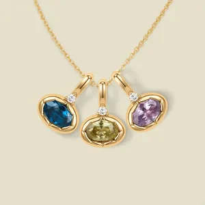 Detailansicht von blauen, olivfarbenen und lila ovalen Edelsteinanhängern in 18K Gold