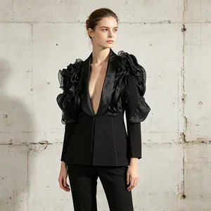 Detailansicht eines schwarzen Blazers mit dramatischen 3D-Rüschenschultern und V-Ausschnitt.