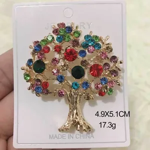 Détail d'une broche en forme d'arbre de vie dorée avec des strass multicolores