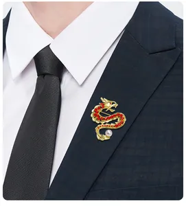 Detailansicht einer goldenen Drachenbrosche mit roten Kristallen am Revers