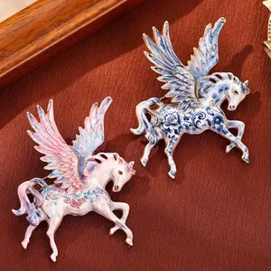Vintage enamel pegasus brooches with intricate floral patterns on textured background